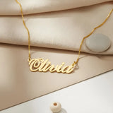 Gold personalized name necklace on a beige fabric background
