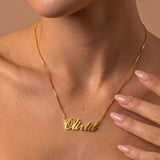 Gold necklace with a name pendant on a person against a neutral background