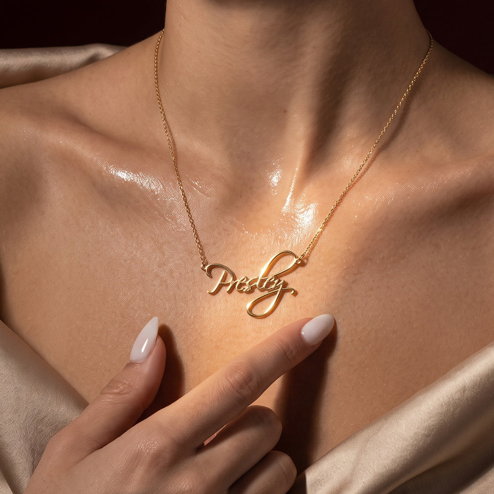 Close-up of a woman wearing a gold plated sterling silver custom name necklace with "Presley" across her collarbone.