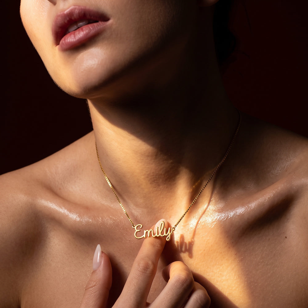 Woman wearing a gold-plated sterling silver personalized "Emily" name necklace, with sunlight accentuating the jewelry.